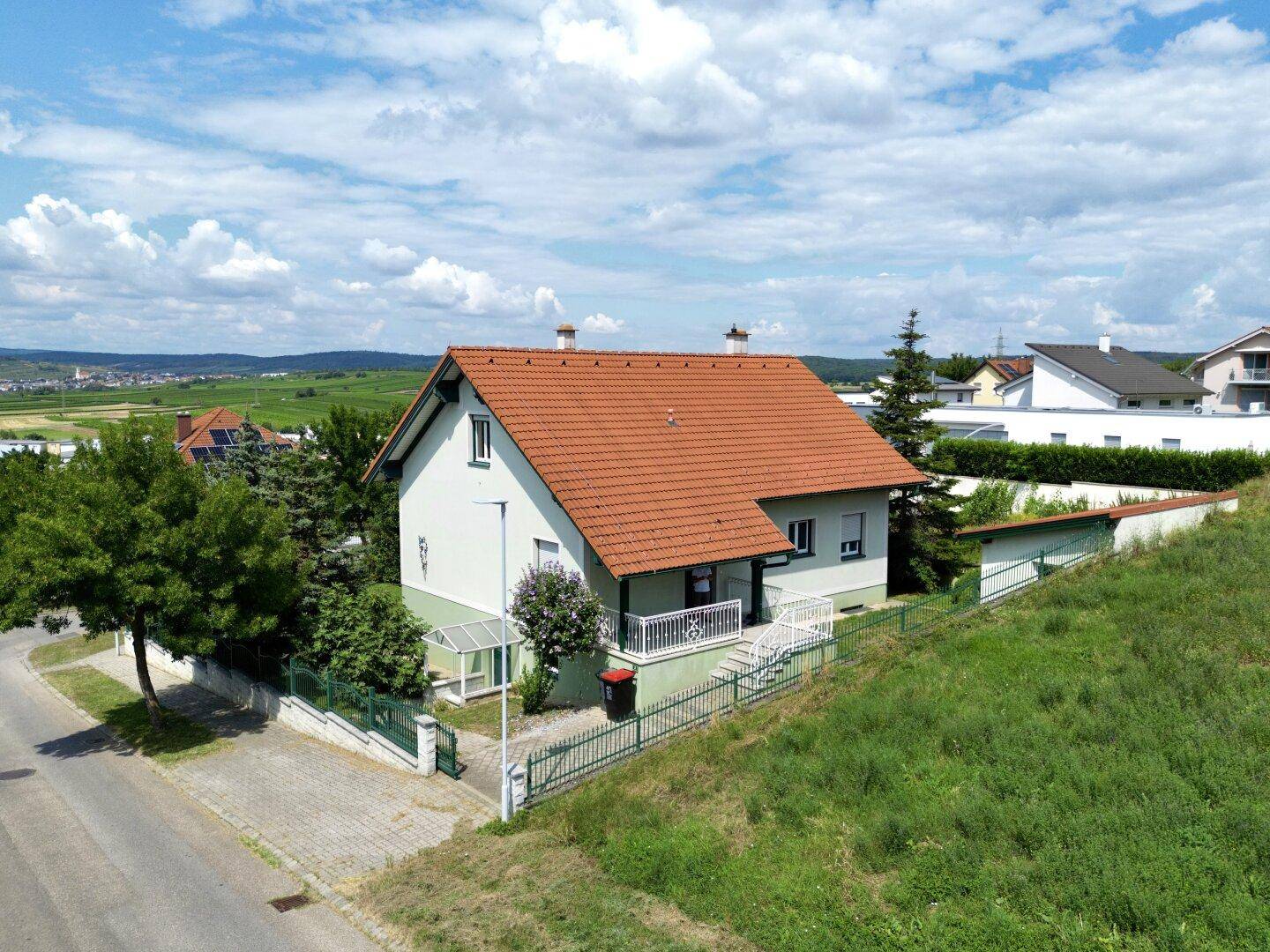 Luftaufnahme eines Einfamilienhauses mit rotem Ziegeldach und umliegender Grünfläche.