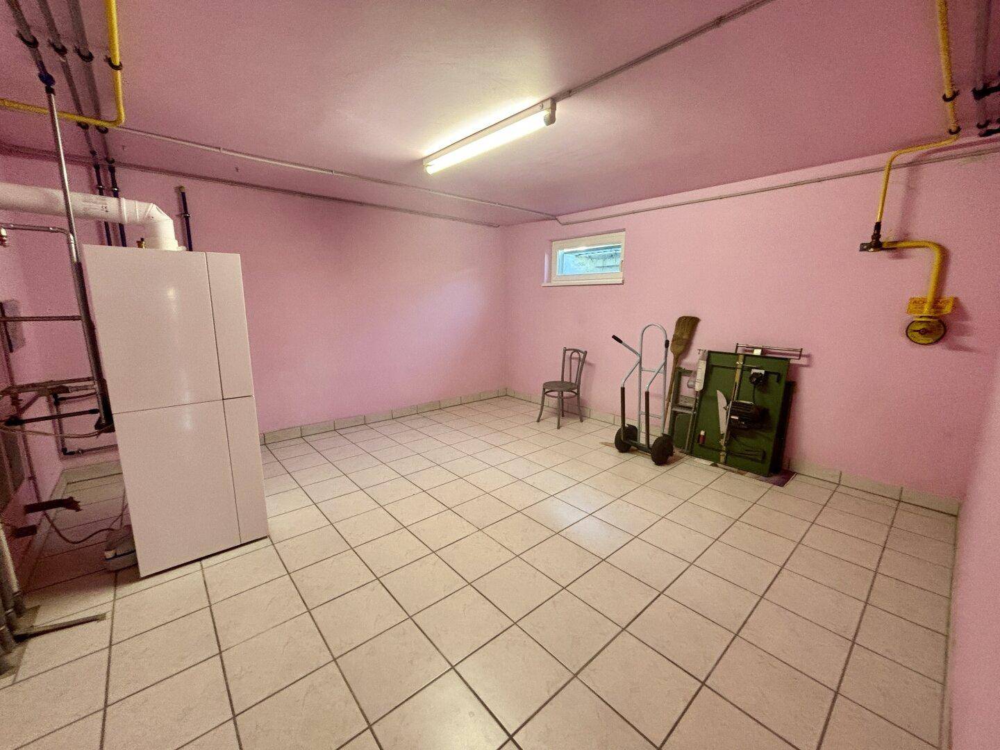 Hauswirtschaftsraum mit Fliesenboden, Heizungsanlage und pink gestrichenen Wänden.