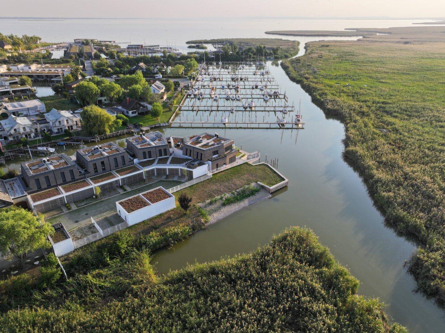 Luftaufnahme der modernen Wohnanlage mit angrenzendem Yachthafen und weitem Blick auf den See.