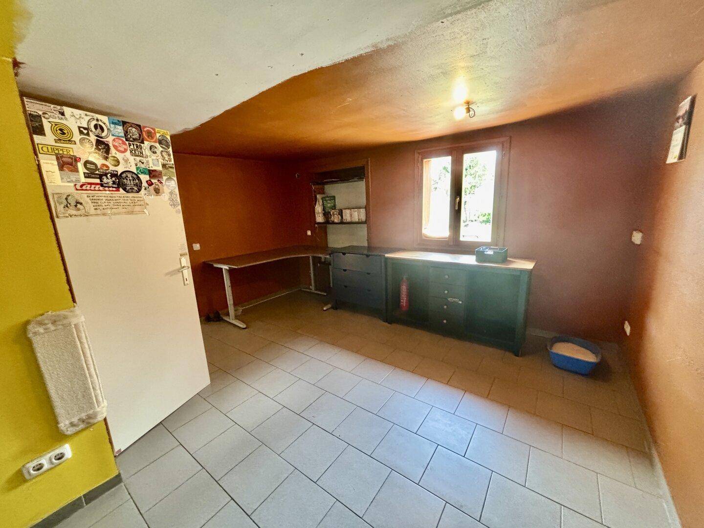 Arbeitszimmer mit Fliesenboden, Schreibtisch und einem Fenster mit Blick ins Grüne, ideal für Home-Office.