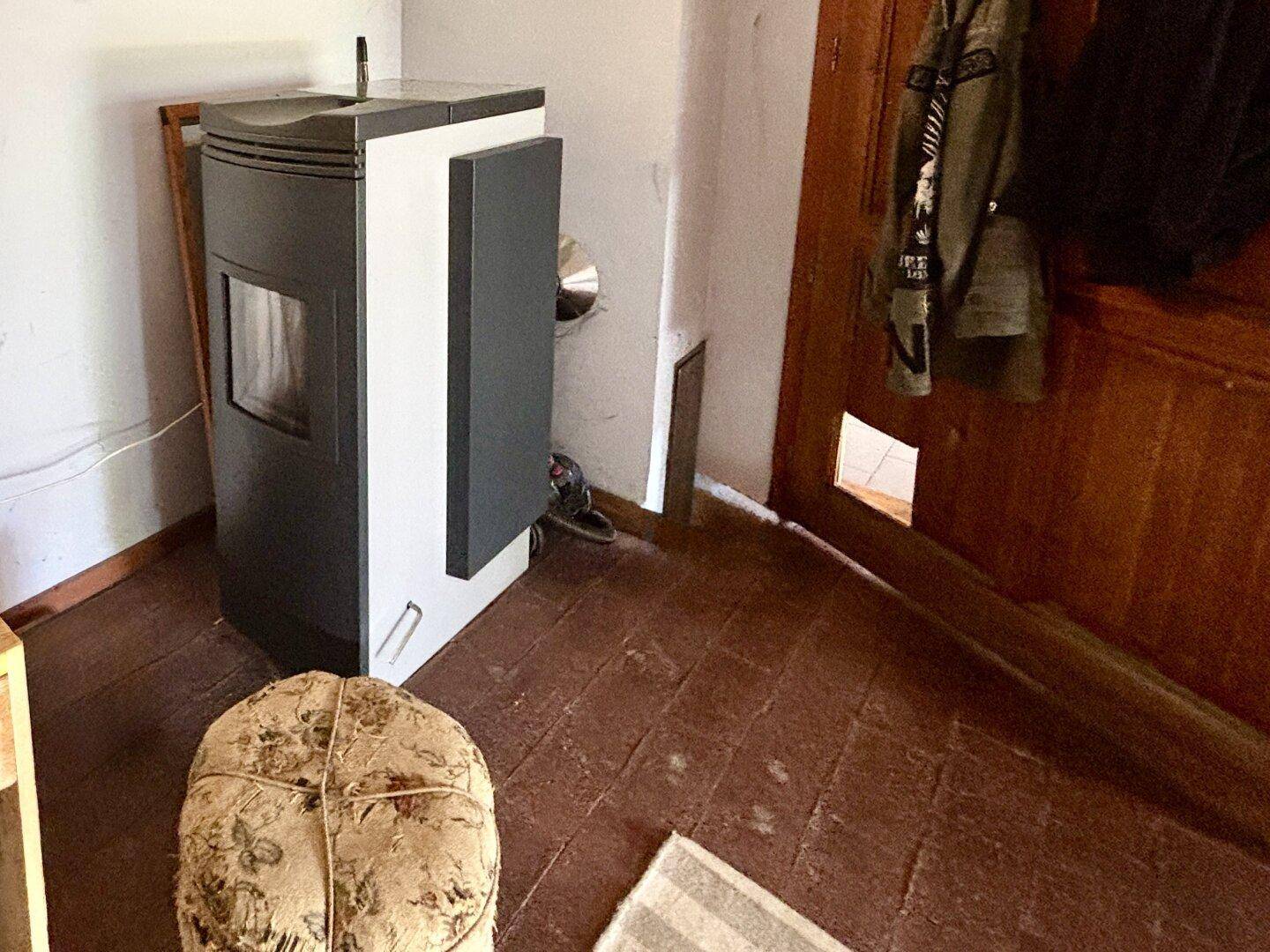 Gemütlicher Raum mit einem modernen Holzofen und Terrakotta-Fliesenboden, der Wärme spendet.