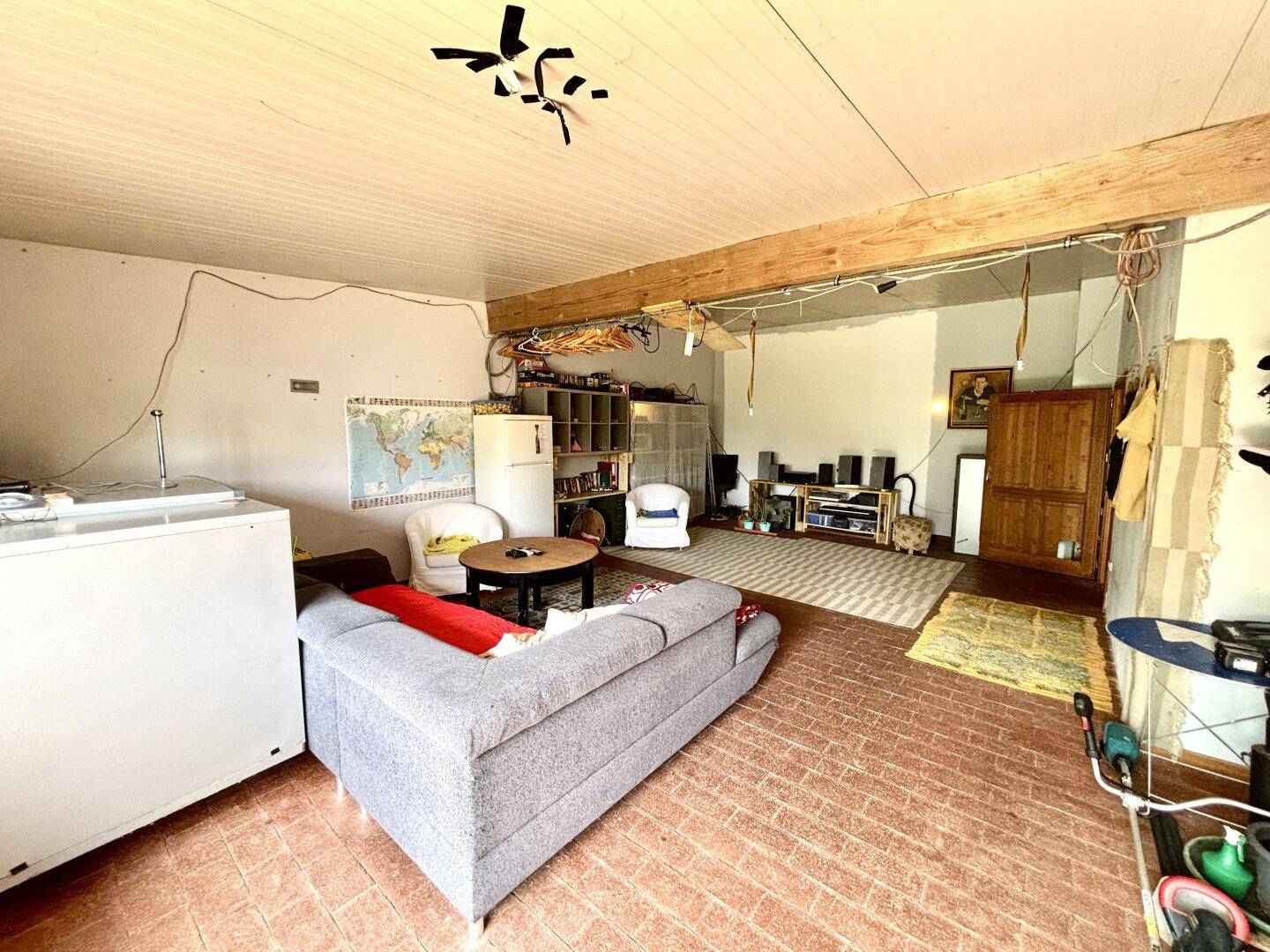 Helles Wohnzimmer mit Sofa, Kühlschrank und Regalen, bietet viel Platz für individuelle Gestaltung.