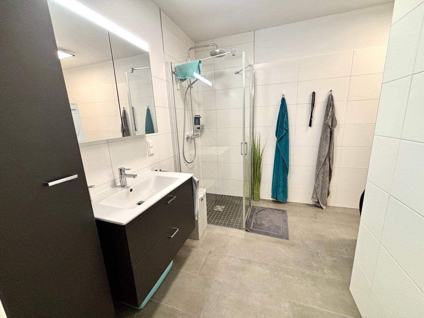 Modernes Badezimmer mit großer ebenerdiger Dusche, Einzelwaschbecken und Spiegelschrank.