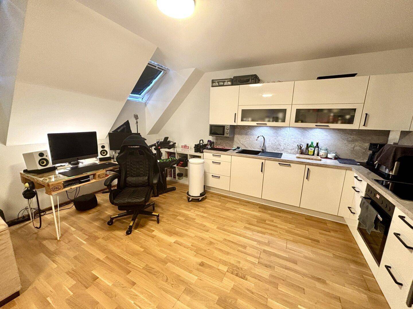 Offener Küchenbereich im Dachgeschoss mit moderner Einbauküche und Arbeitsplatz unter dem Dachfenster.