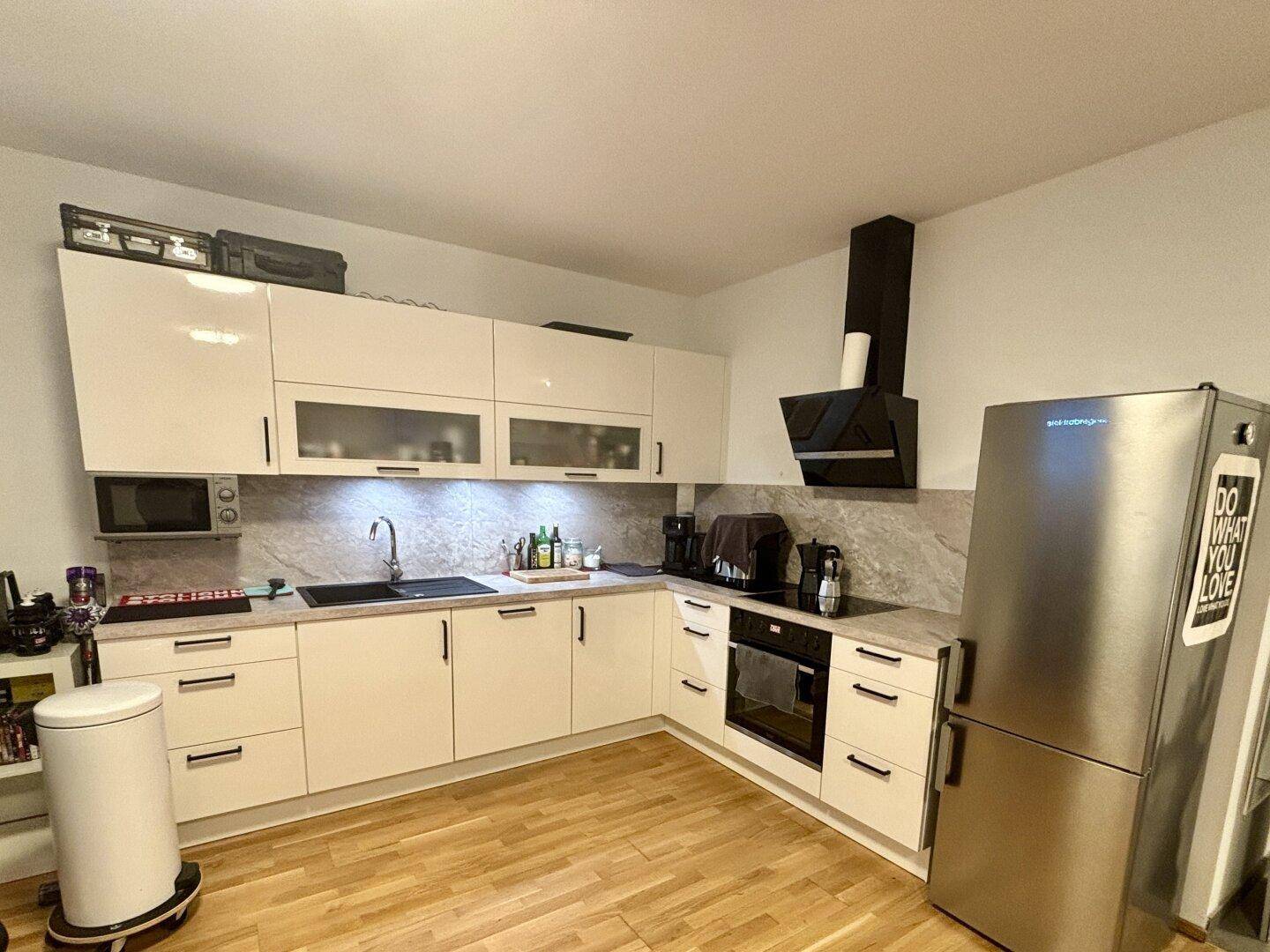 Moderne weiße Einbauküche mit Hochglanzfronten, integrierten Geräten und großem Kühlschrank.