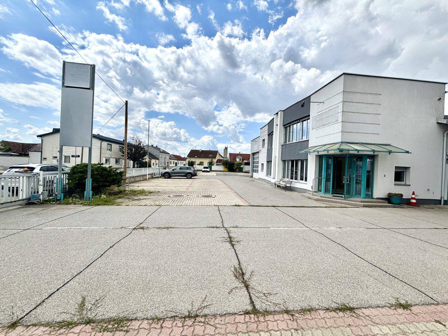 Ansicht des Geschäftsgebäudes von der Straße mit Parkplätzen und einem Schild im Vordergrund.
