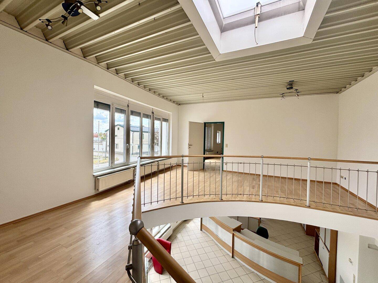 Offener Flur im Obergeschoss mit Holzboden, Geländer und einem Dachfenster für natürliches Licht.
