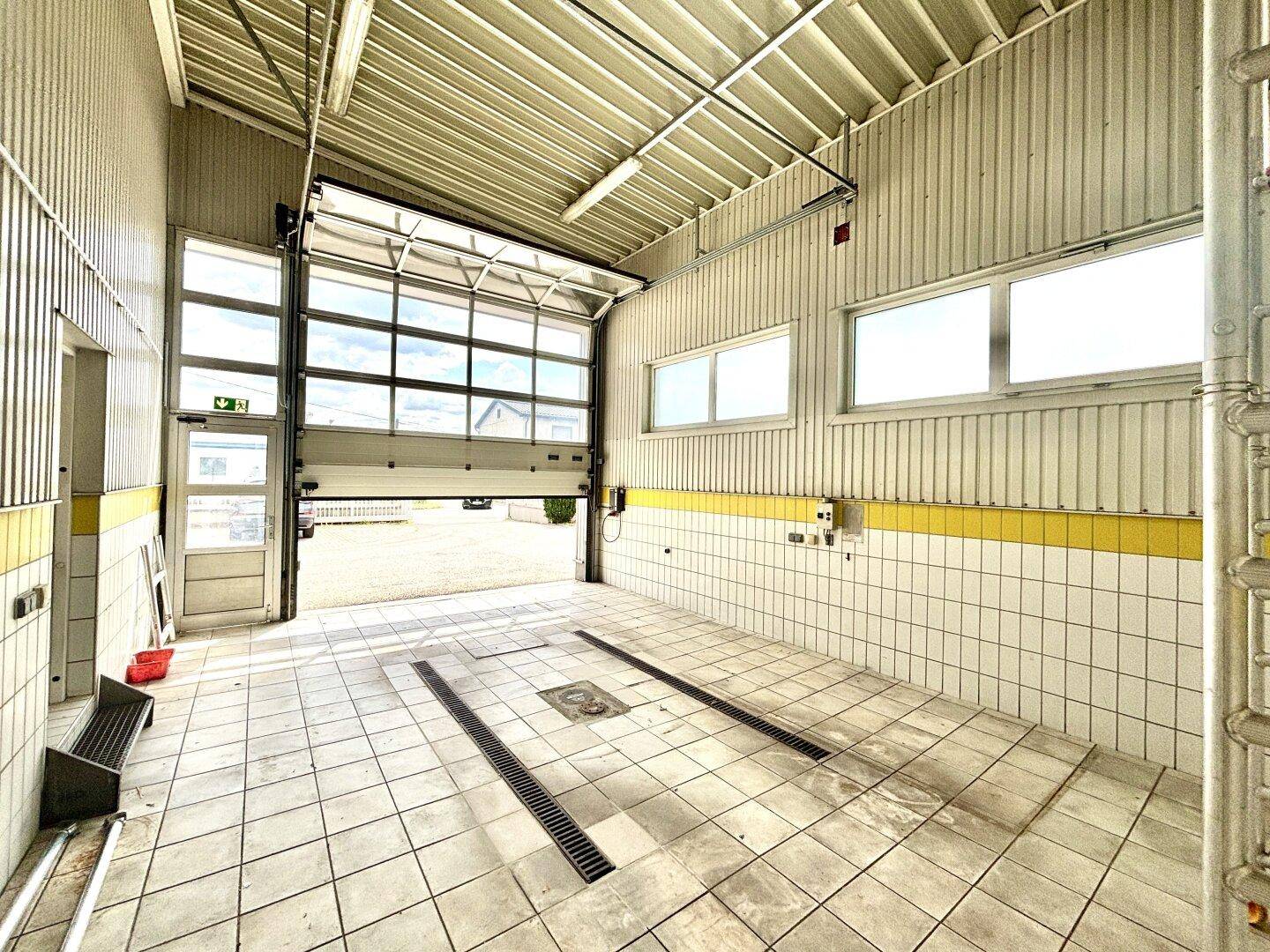 Geräumige Garage oder Werkstatt mit Fliesenboden, Rolltor und Inspektionsgruben.