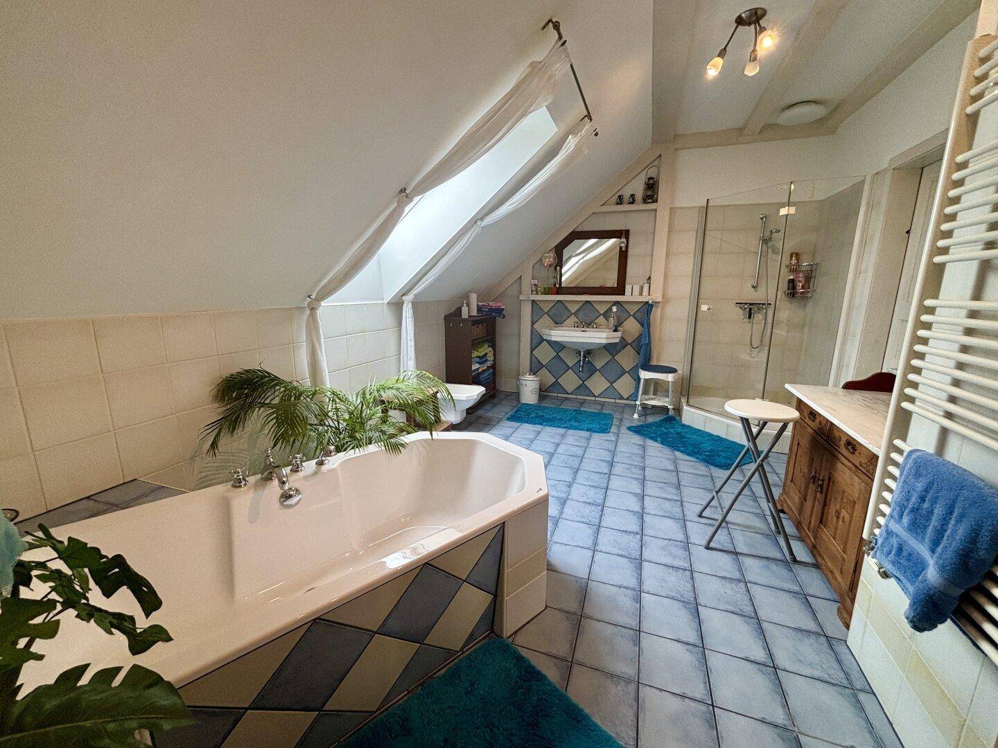 Geräumiges Badezimmer im Dachgeschoss mit Badewanne, Dusche und Dachfenstern.