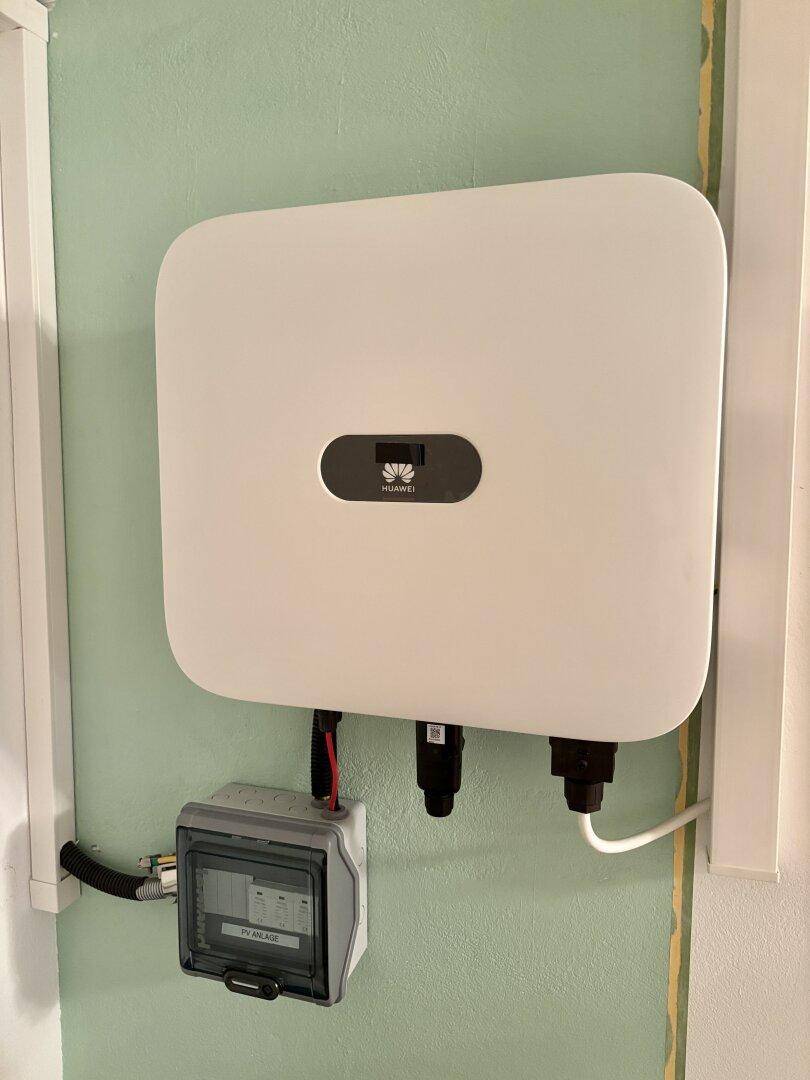 Photovoltaik-Wechselrichter an einer hellgrünen Wand installiert.