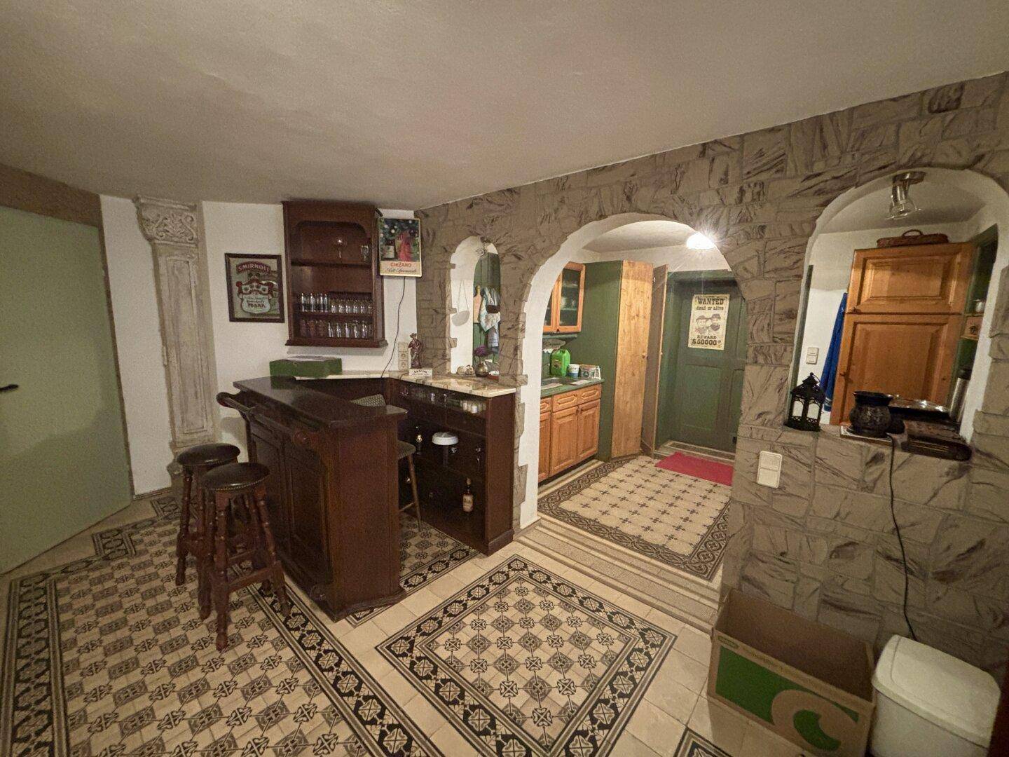 Gemütlicher Barbereich im Keller mit rustikalen Steinwänden und traditionellem Fliesenboden.