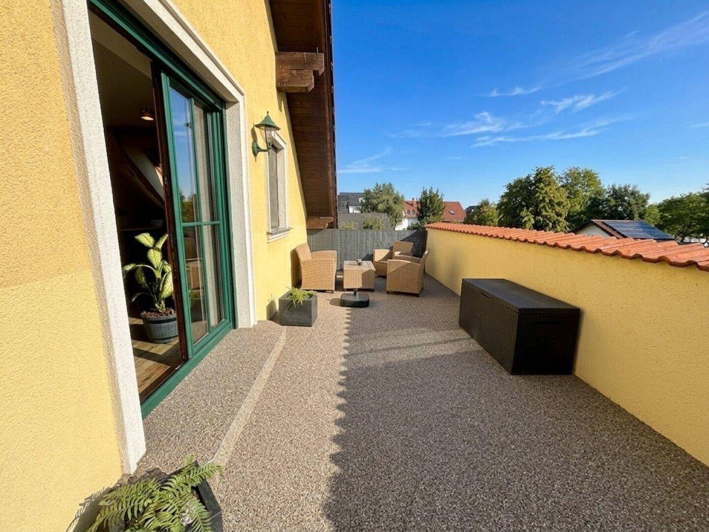 Sonniger Terrassenbereich mit bequemen Loungemöbeln und Blick auf die Umgebung.