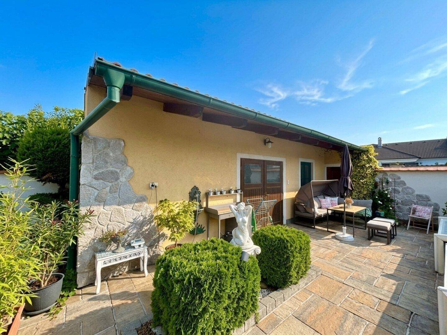Kleines Nebengebäude mit gepflasterter Terrasse und gemütlicher Sitzecke im Freien.