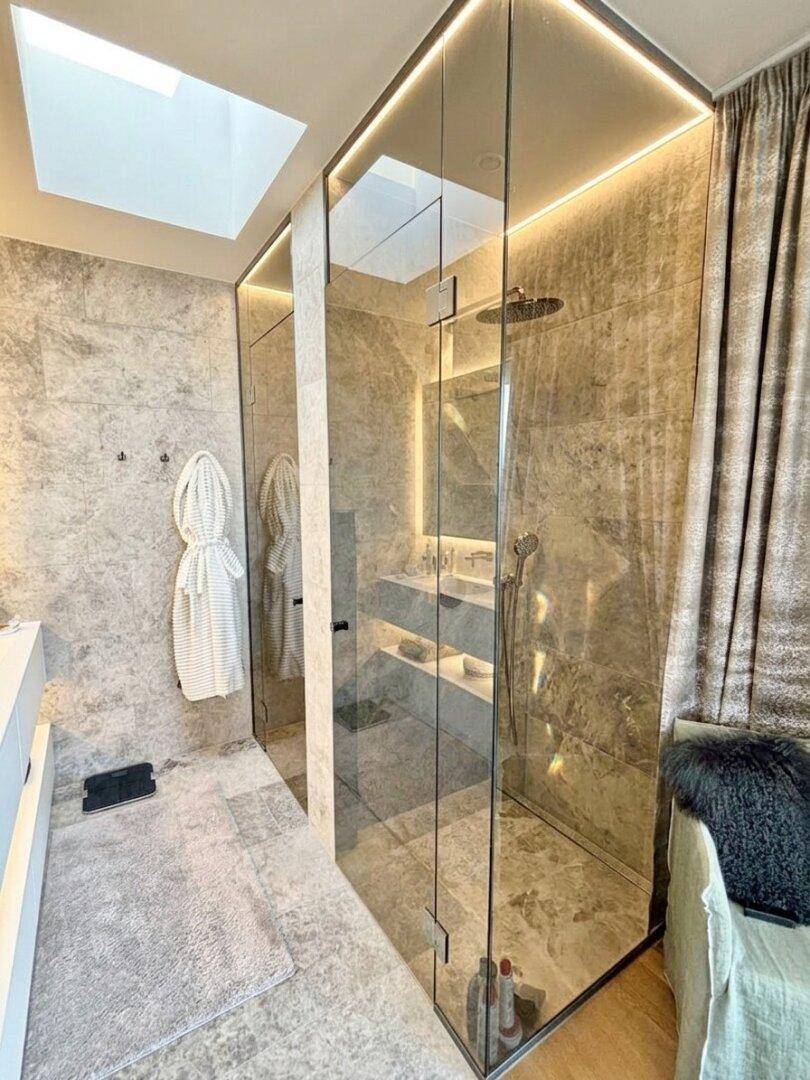 Modernes Badezimmer mit großer begehbarer Dusche, Fliesenboden und Oberlicht.
