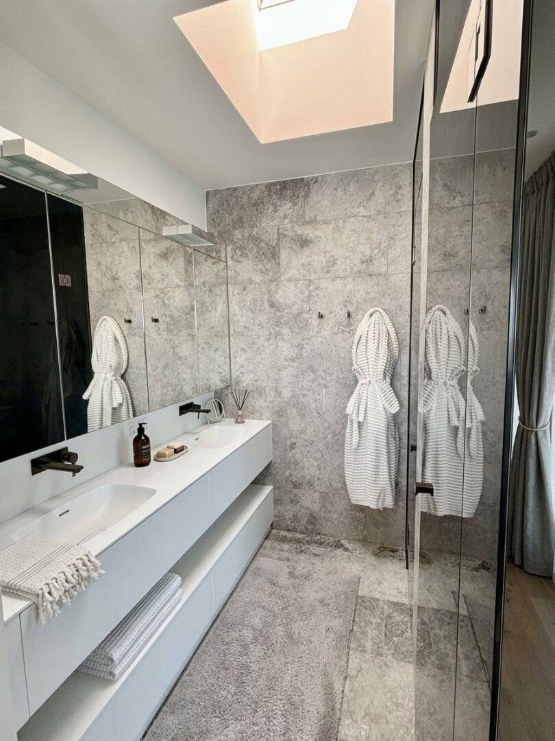 Elegantes Badezimmer mit Doppelwaschbecken, großem Spiegel und modernen Armaturen.