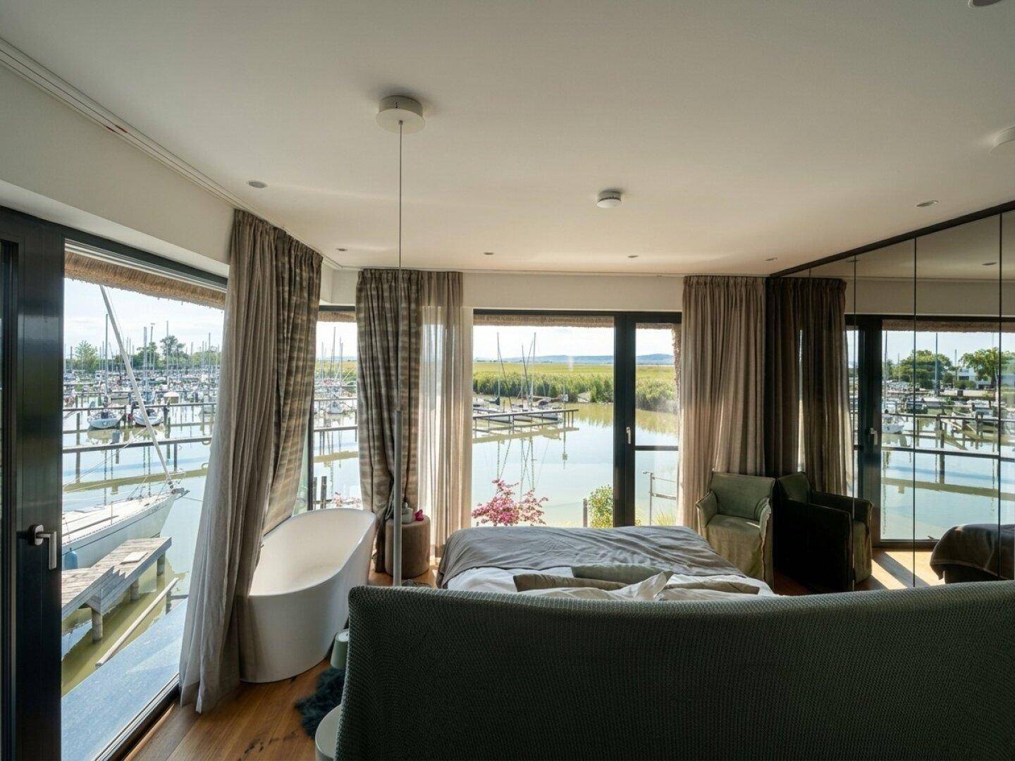 Helles Schlafzimmer mit Panoramablick auf den See und direktem Zugang zum Außenbereich.