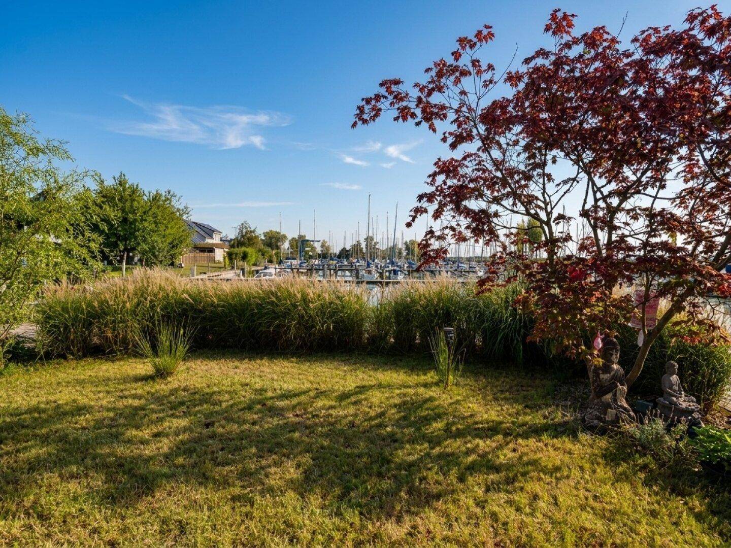 Gepflegter Gartenbereich mit Rasenfläche und Blick auf den Yachthafen.