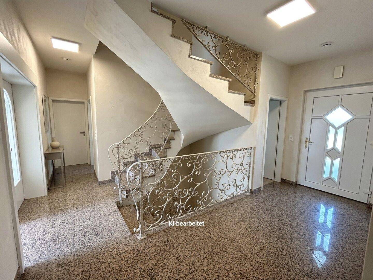 Geräumiger Eingangsbereich mit eleganter Wendeltreppe und kunstvollem Geländer.