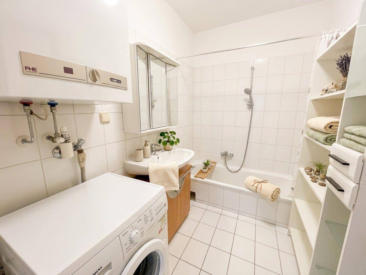 Funktionales Badezimmer mit Badewanne, Waschbecken und Waschmaschine.