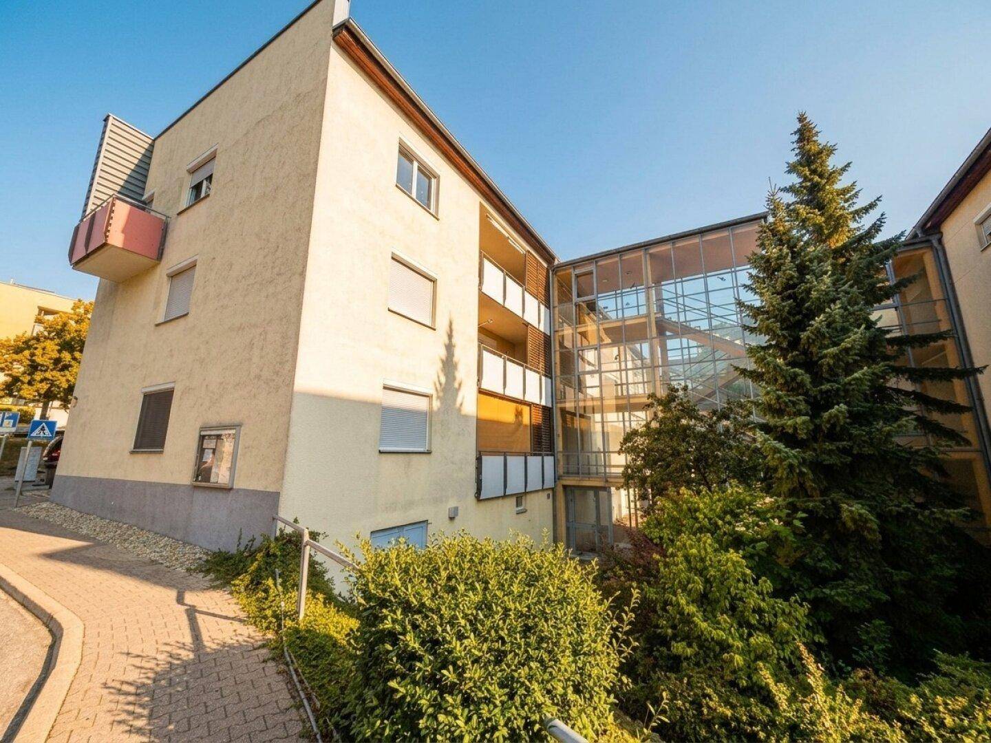Gebäudefassade mit Balkonen und einem modernen, verglasten Treppenhaus.
