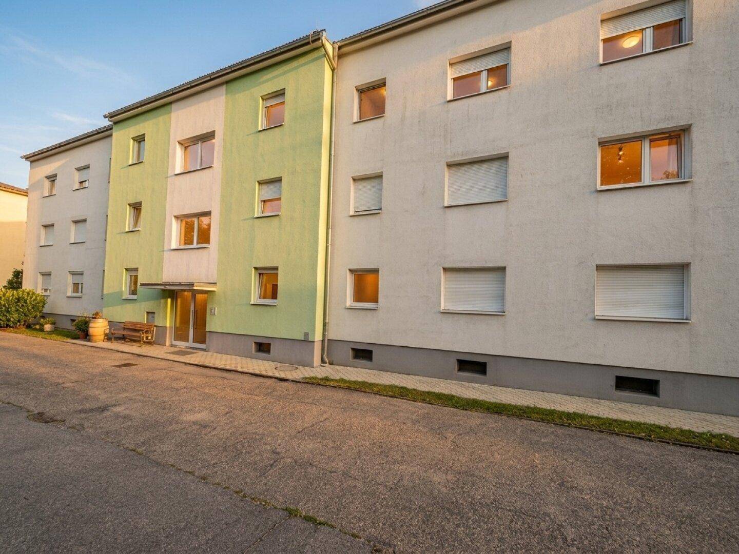 Mehrfamilienhaus mit einer hellgrünen und weißen Fassade und mehreren Fenstern.