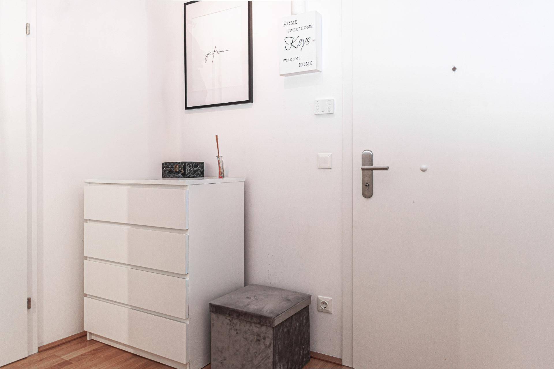 Heller Eingangsbereich mit Holzboden, Kommode und moderner Dekoration.