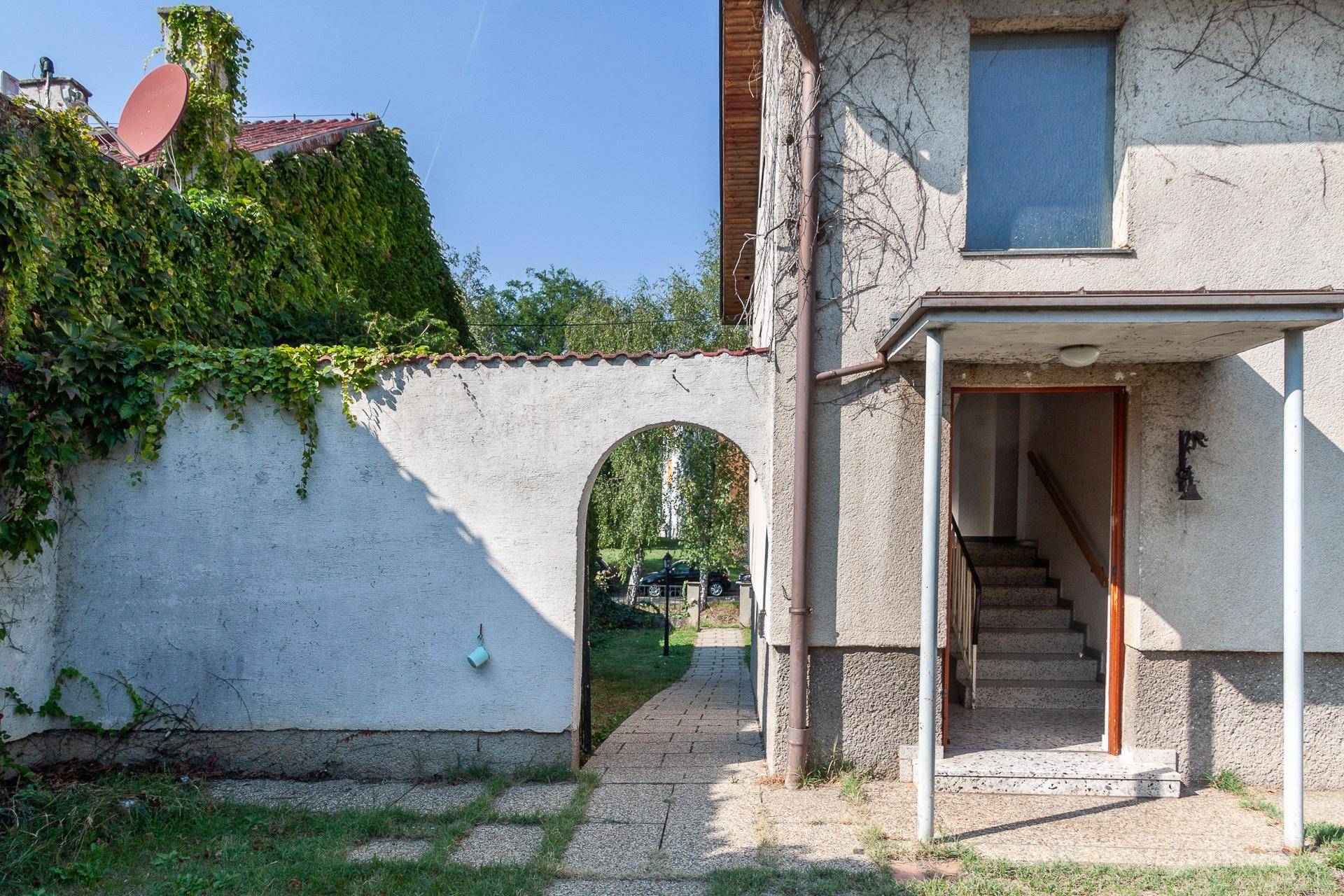 Eingangsbereich des Hauses mit überdachtem Zugang und einem Bogen zum hinteren Garten.