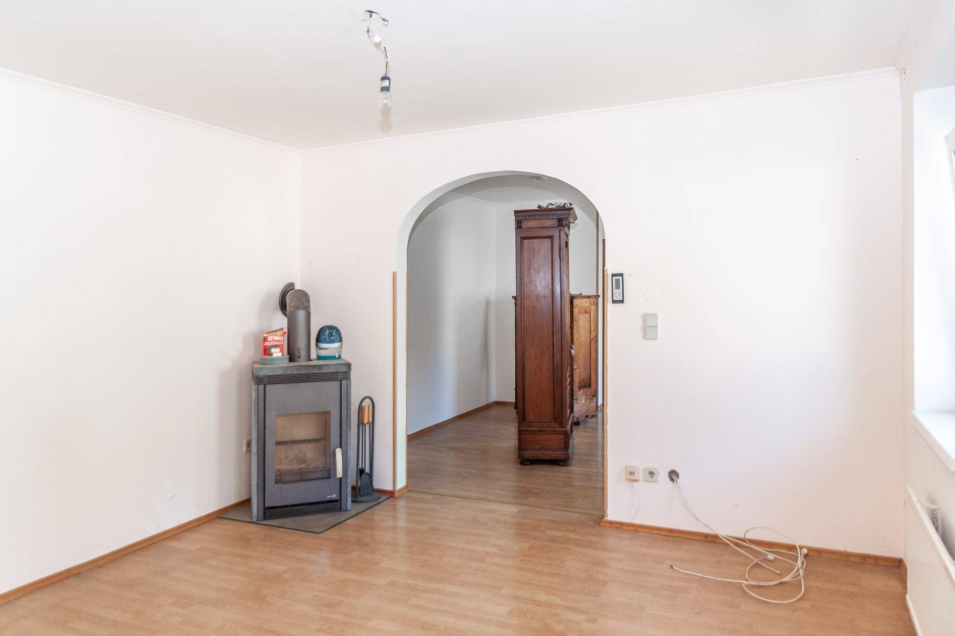 Wohnzimmer mit Laminatboden und einem modernen Holzofen, der Gemütlichkeit verspricht.