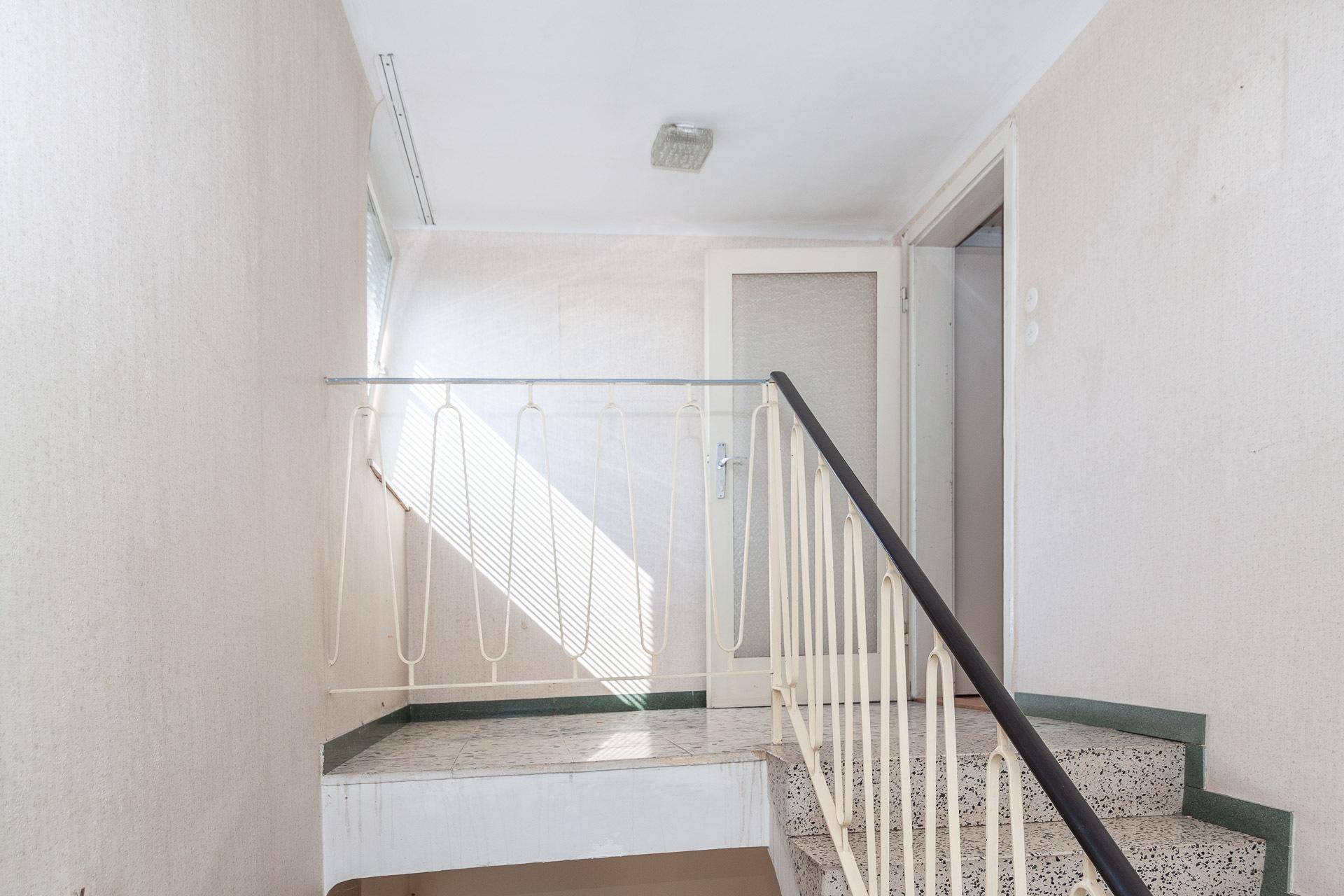Treppenhaus mit Terrazzostufen und Geländer, das die oberen Etagen erschließt.