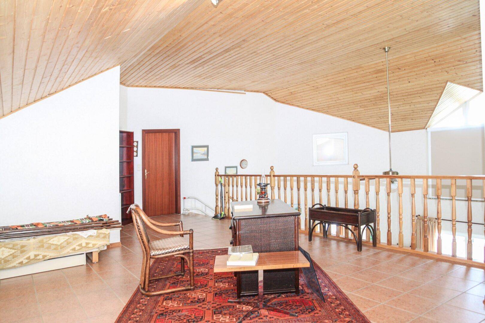 Helle Galerie im Dachgeschoss mit Holzverkleidung an der Decke und Fliesenboden.