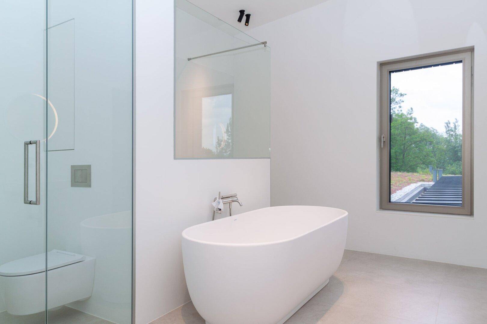 Modernes Badezimmer mit freistehender Badewanne, separater Dusche und Fenster mit Ausblick.