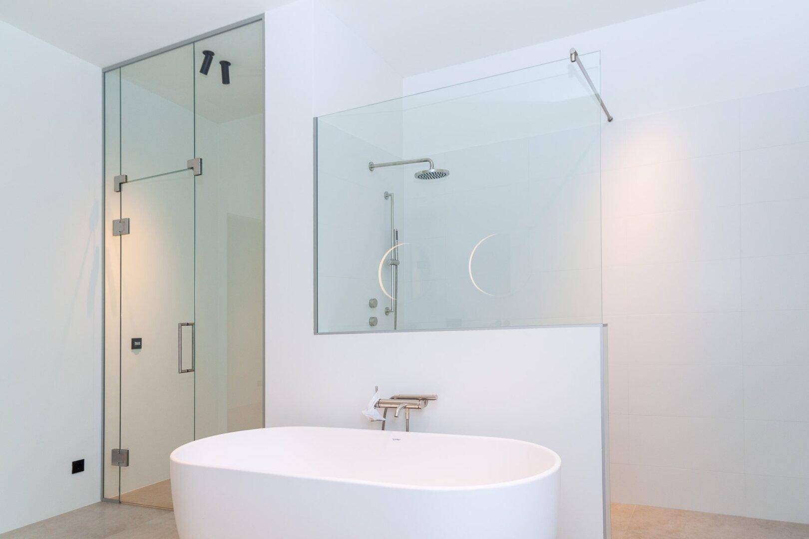 Modernes Badezimmer mit freistehender Badewanne und großer Glasdusche mit Regenduschkopf.