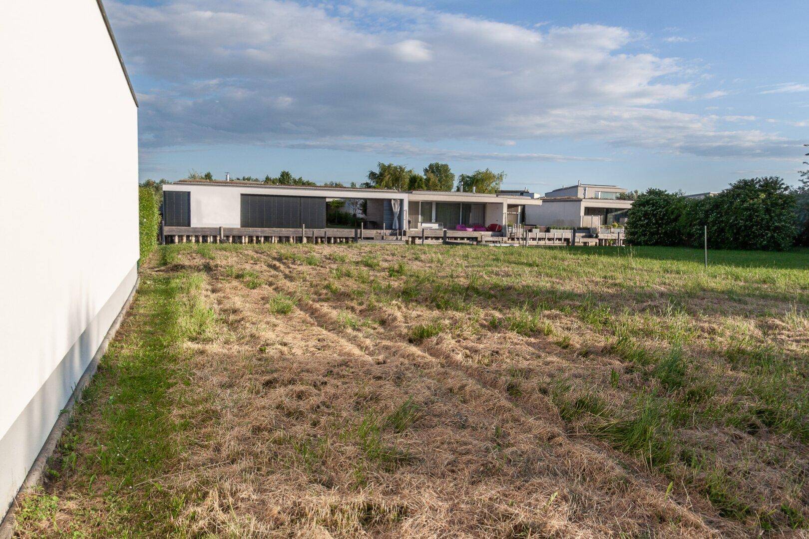 Moderne Architektur mit klaren Linien und einer weiten, trockenen Rasenfläche vor dem Gebäude.