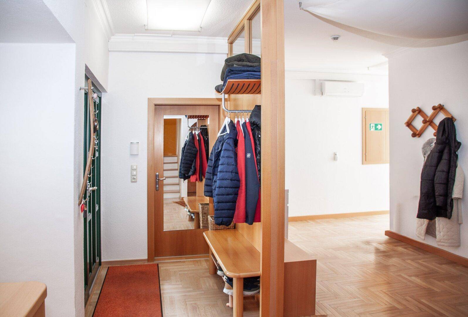 Geräumiger Flur mit Garderobe, Holzbank und Parkettboden, ideal für den Empfang.