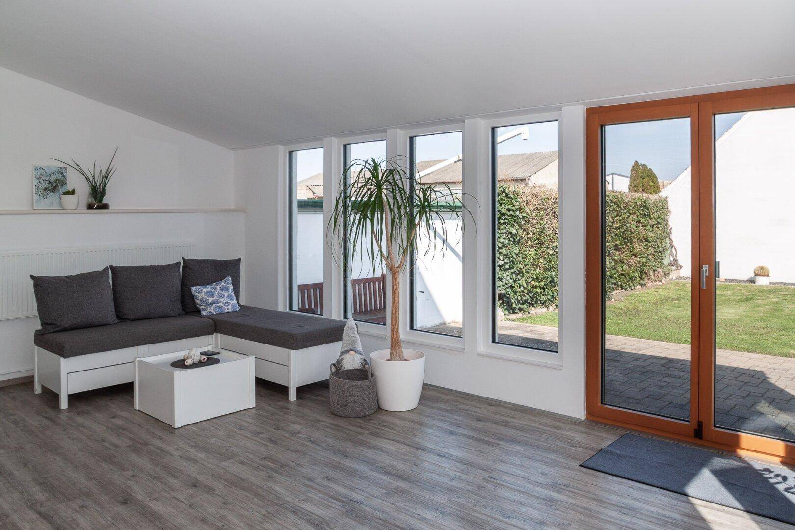 Helles Wohnzimmer mit großen Fenstern und direktem Zugang zum grünen Garten.