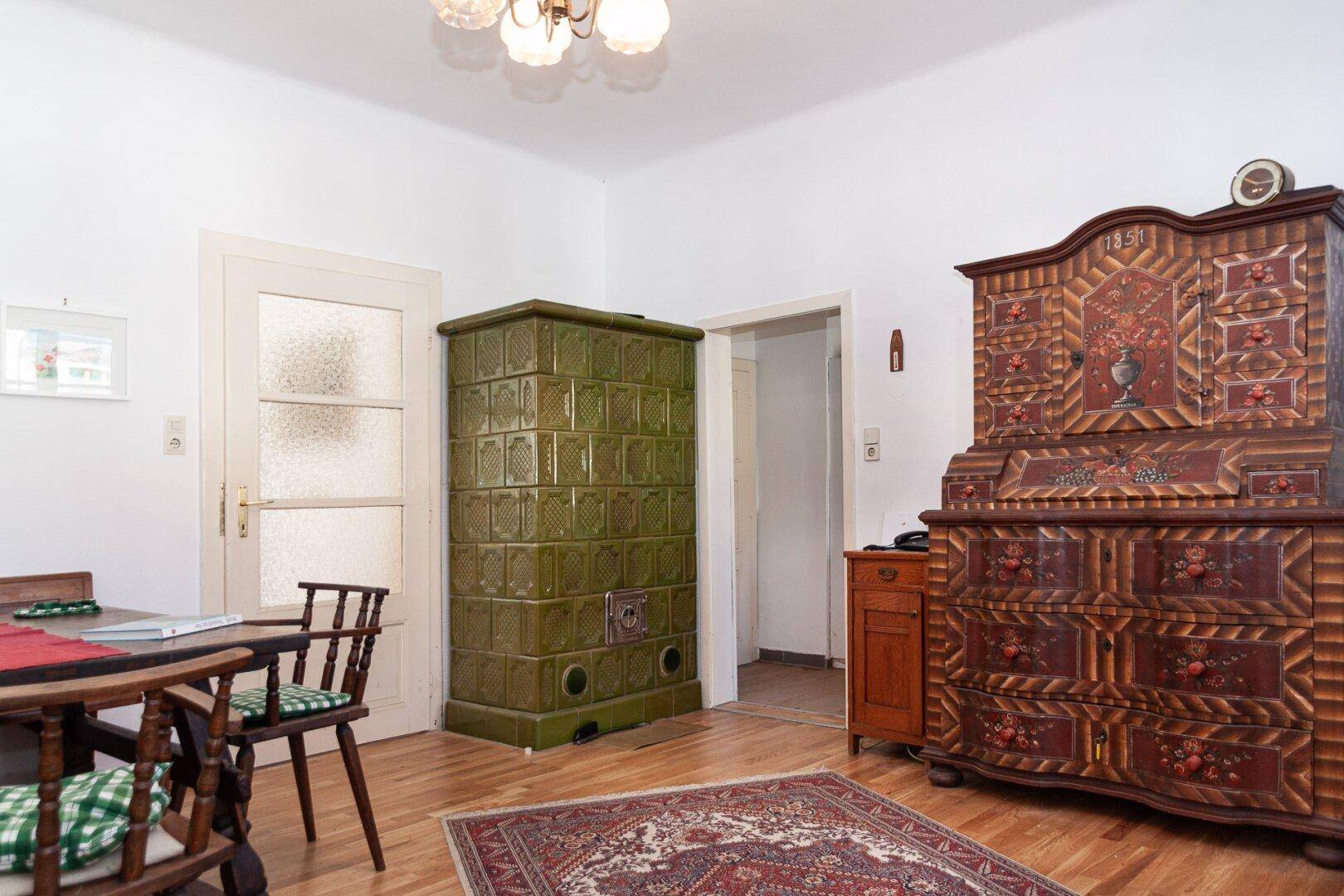 Wohnzimmer mit traditionellem Kachelofen, Holzboden und antiken Möbeln.