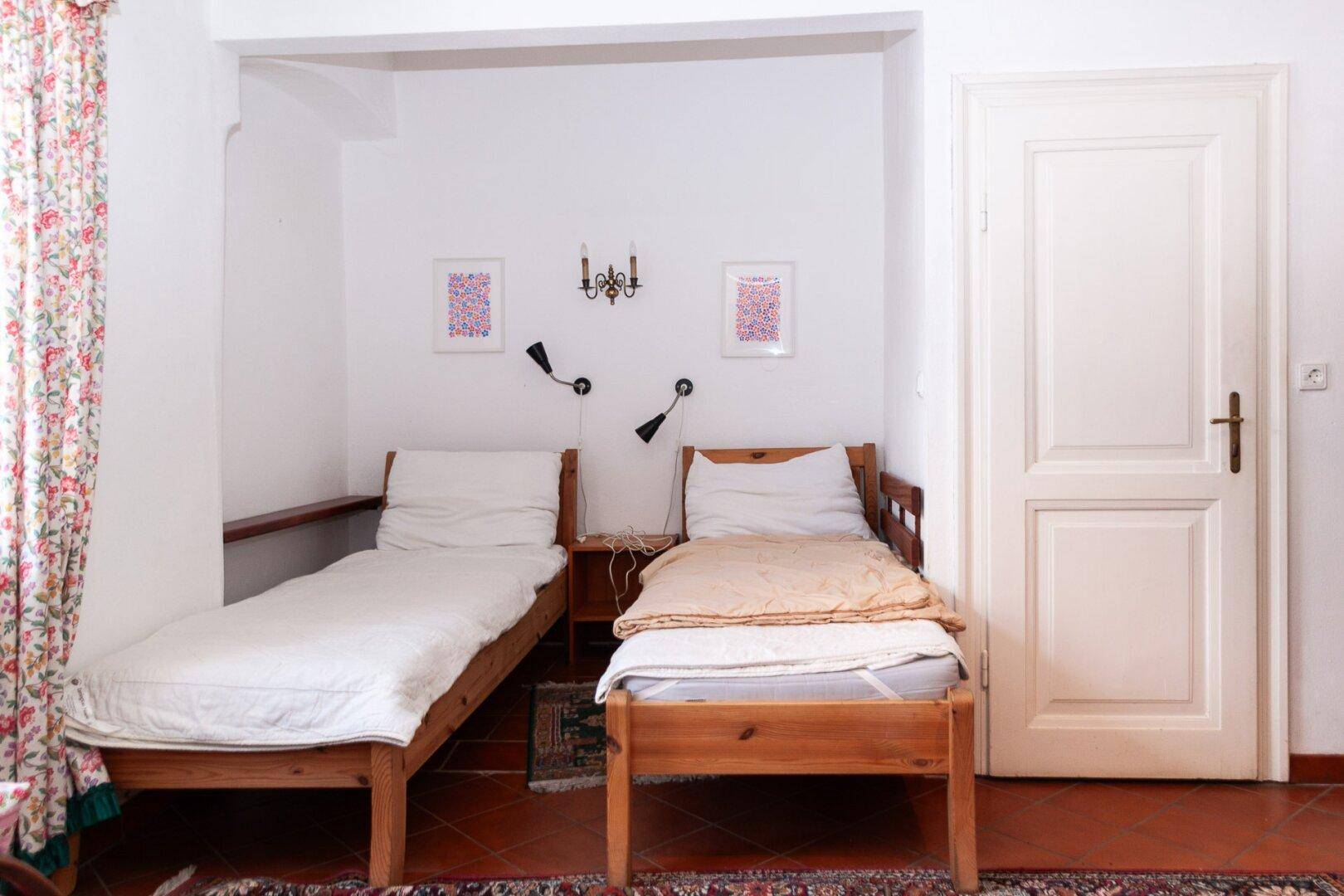 Schlafzimmer mit zwei Einzelbetten, Terrakotta-Fliesenboden und traditionellen Vorhängen.
