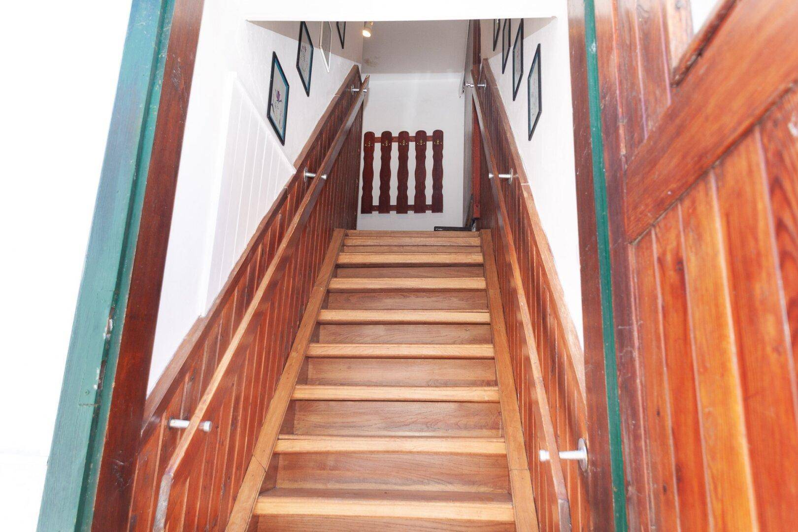 Holztreppe mit Holzgeländer führt in die obere Etage des Hauses.