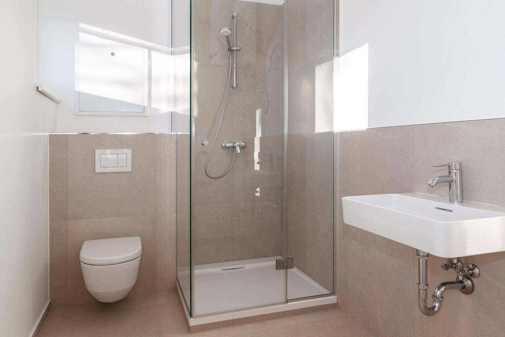 Modernes Badezimmer mit begehbarer Dusche, Wand-WC und kleinem Waschbecken in neutralen Farbtönen.