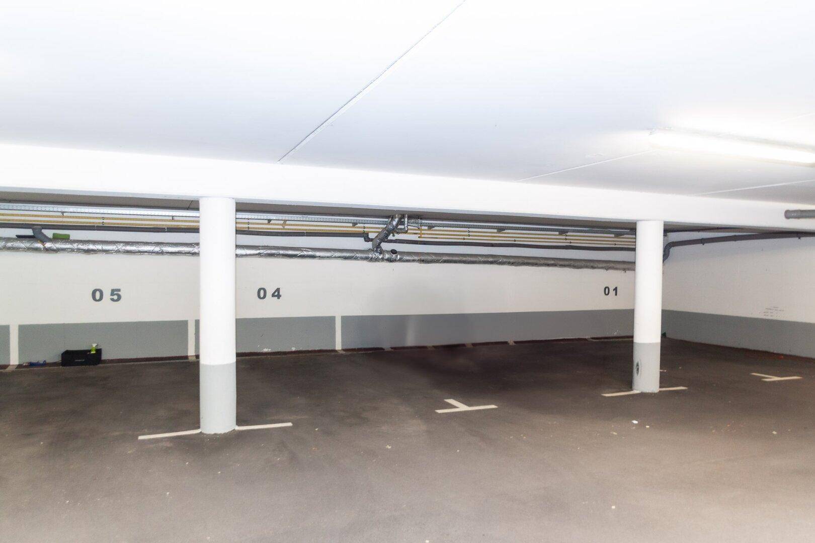 Geräumige Tiefgarage mit markierten Stellplätzen und Säulen, gut beleuchtet.