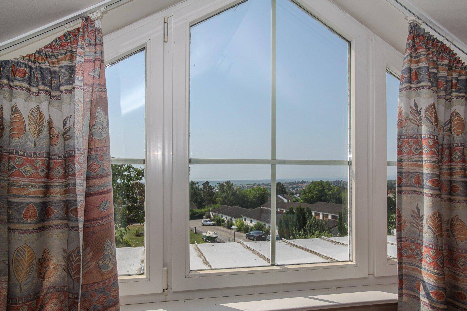 Großes Giebelfenster mit weitem Blick über die Dächer und die Landschaft.
