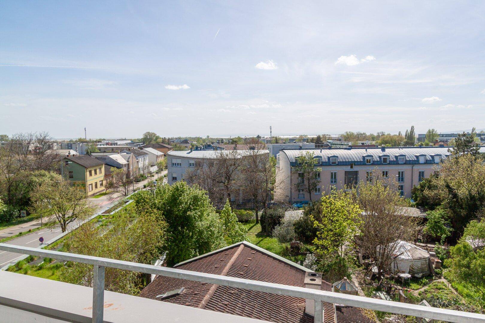 Panoramablick von einem Balkon über eine grüne Wohngegend mit Häusern und Bäumen.
