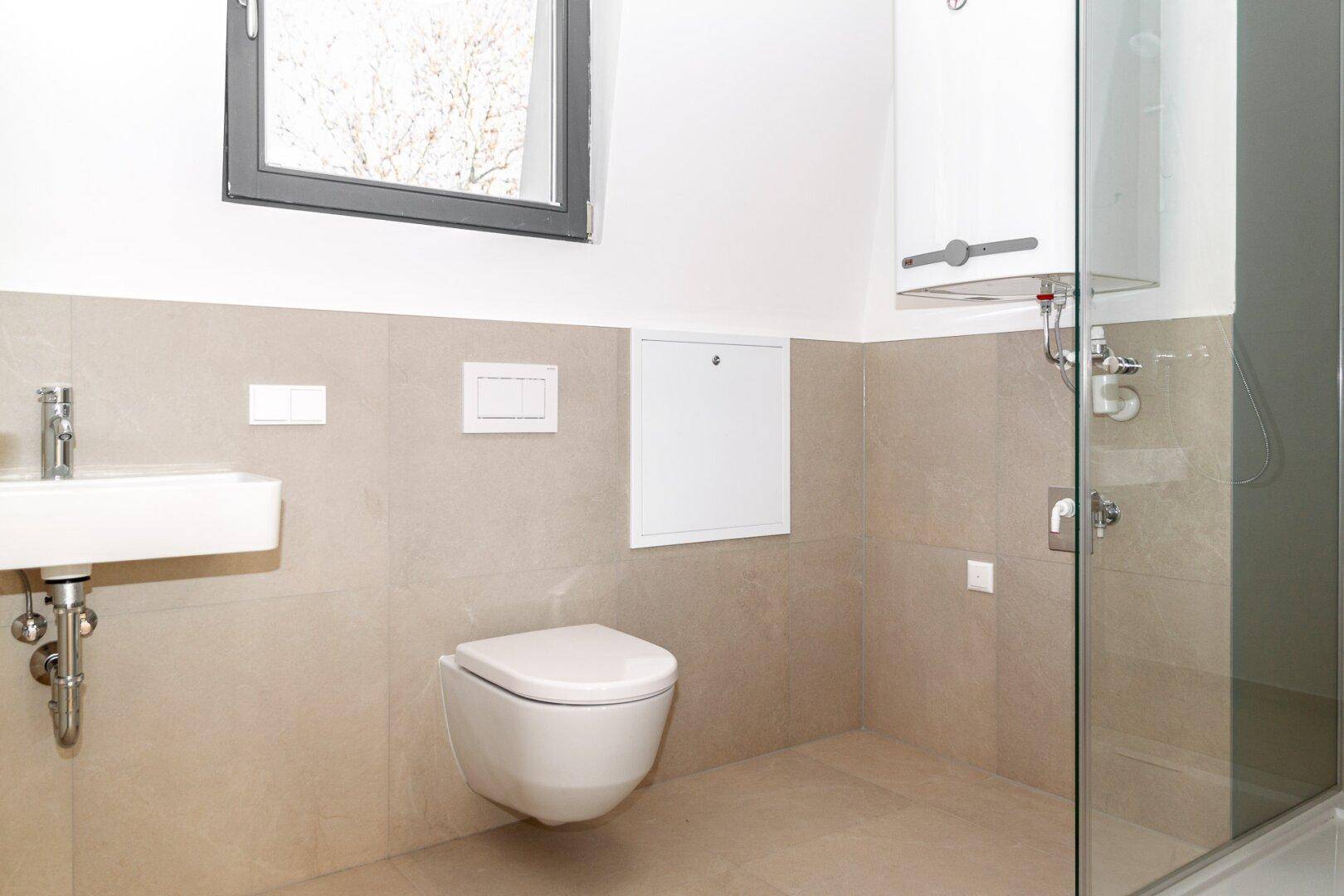 Modernes Badezimmer mit beigefarbenen Fliesen, wandhängendem WC und Duschbereich.