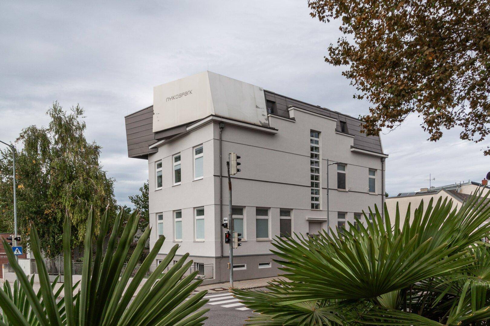 Modernes Wohngebäude mit heller Fassade und markanter Architektur in städtischer Umgebung.