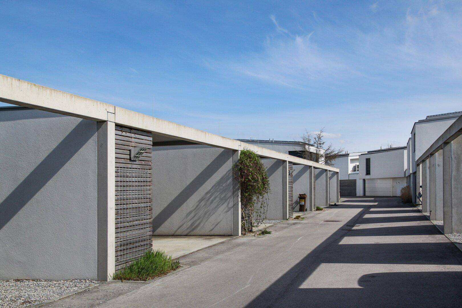 Reihe moderner Carports aus Beton entlang einer Zufahrtsstraße.