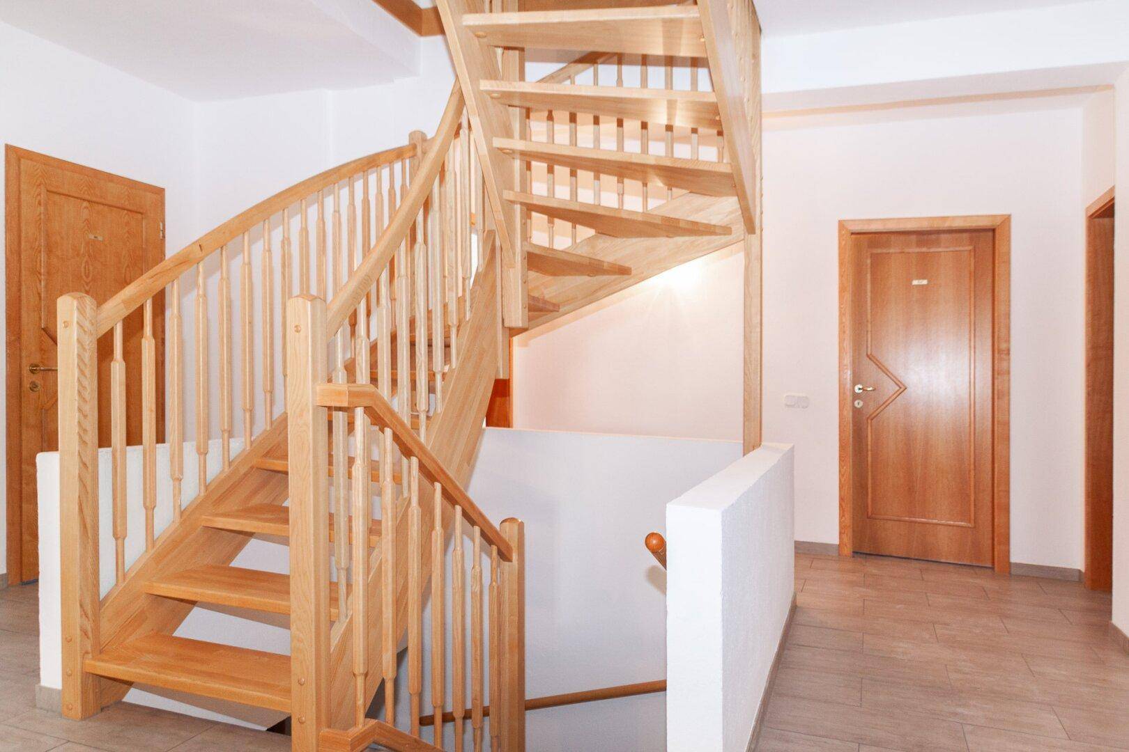 Heller Flur mit einer eleganten Holztreppe, die die verschiedenen Etagen verbindet.
