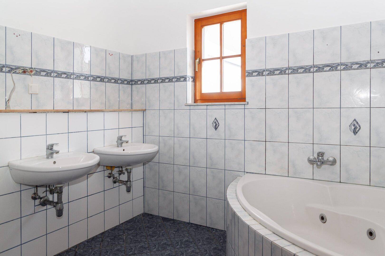 Geräumiges Badezimmer mit Eckbadewanne, Doppelwaschbecken und Fliesen in Blau und Weiß.