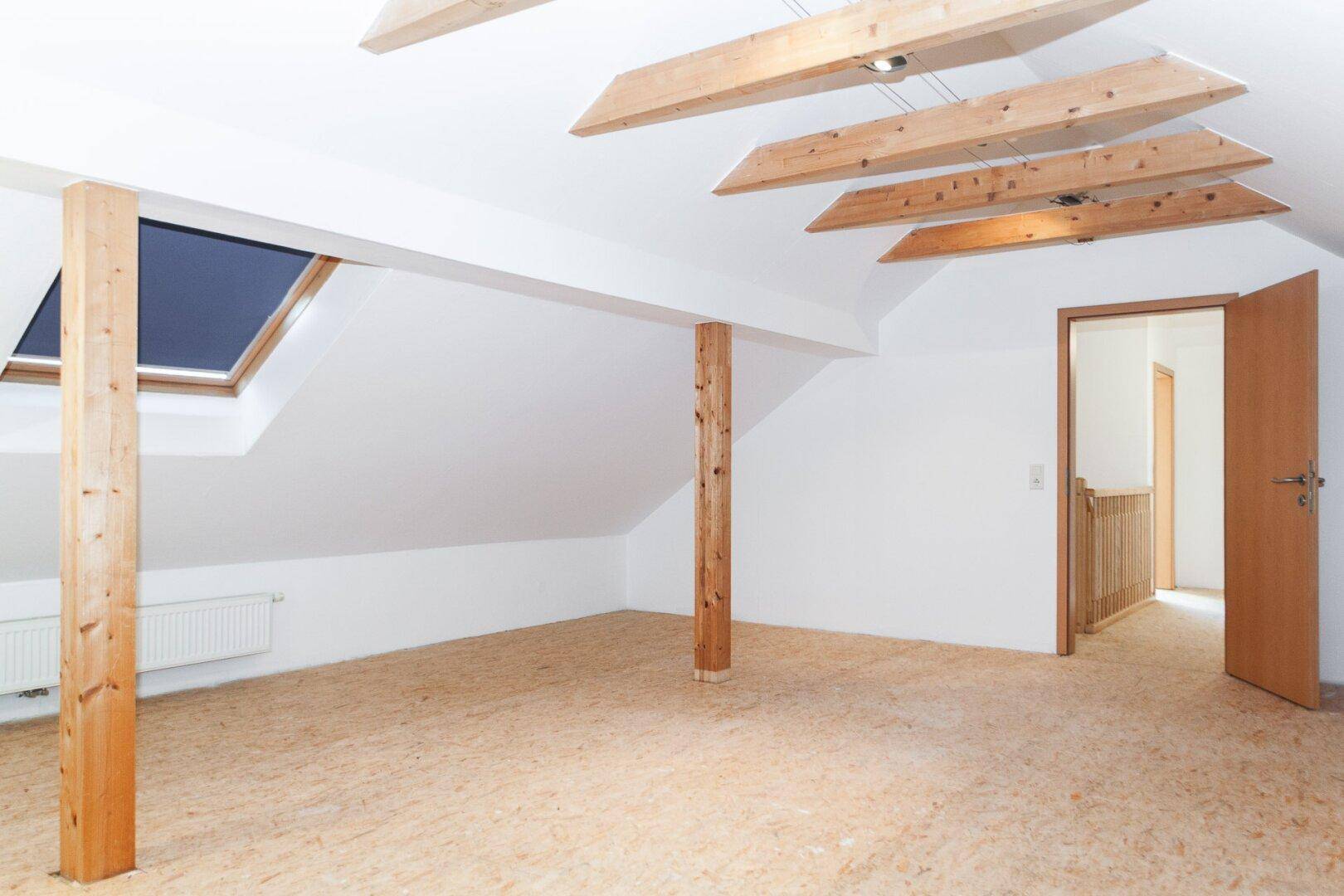 Ausgebauter Dachboden mit Holzbalken, Dachfenster und viel Potenzial zur Nutzung.