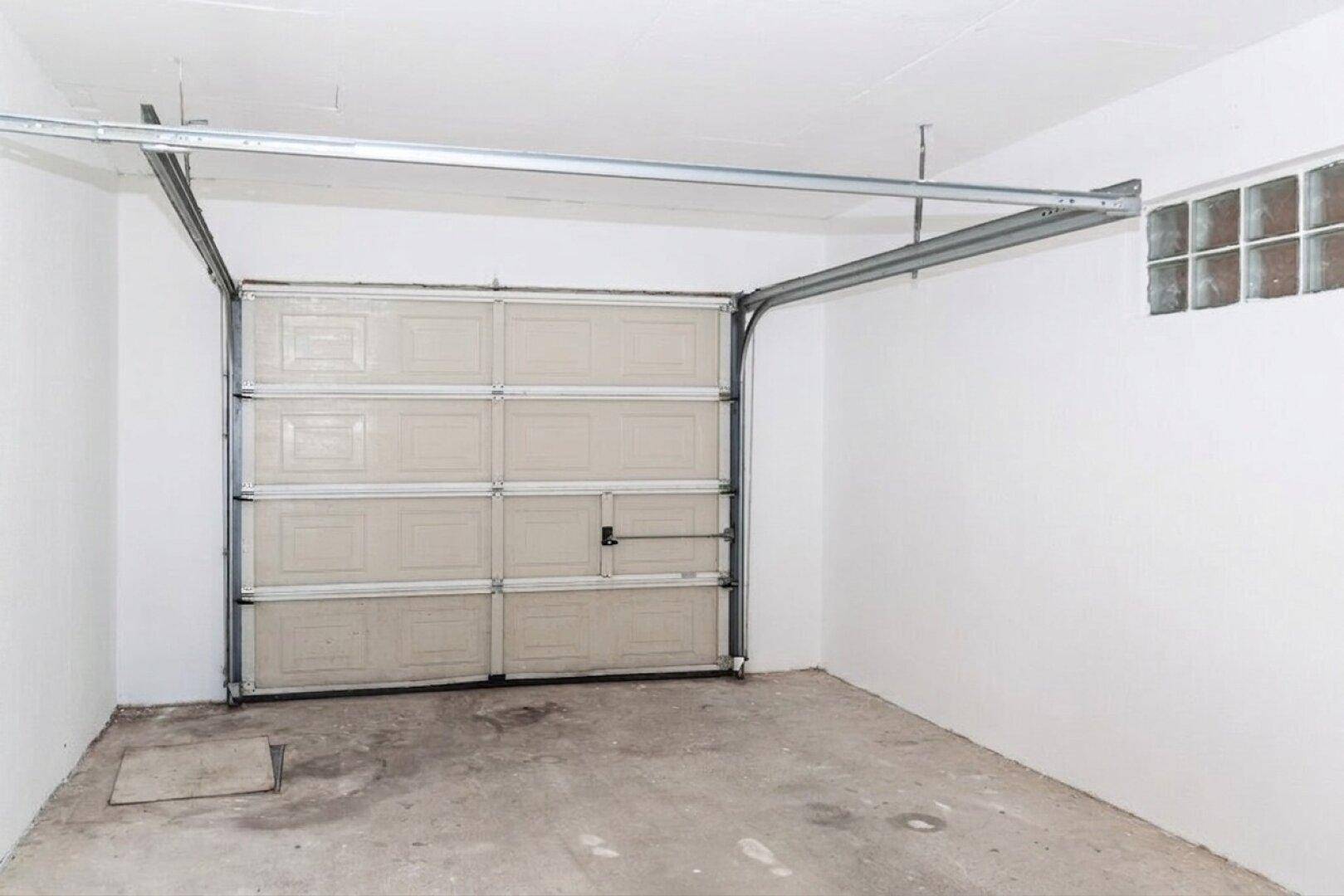 Saubere und geräumige Garage mit Sektionaltor und einem kleinen Fenster.