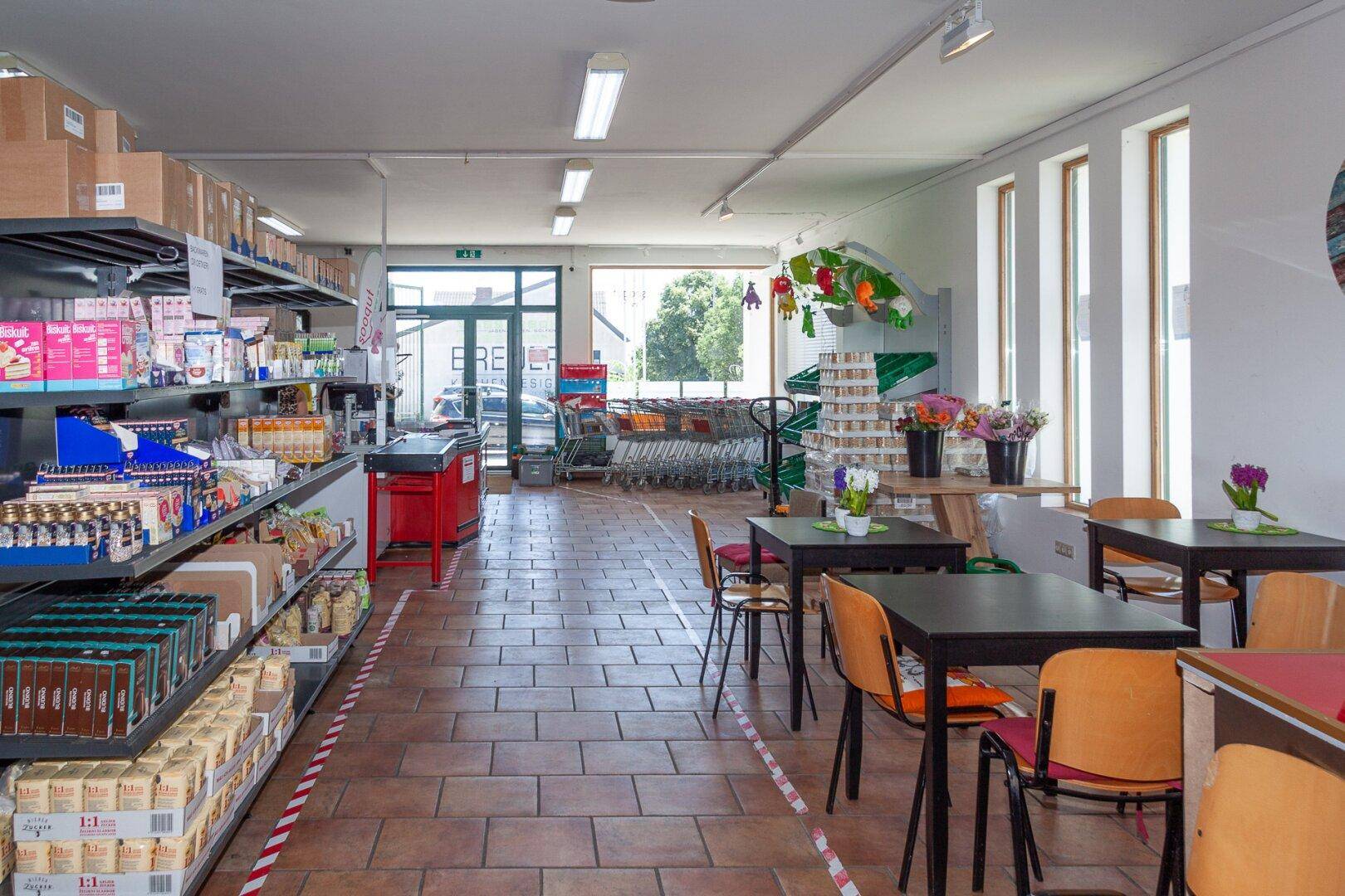 Verkaufsfläche mit Einkaufswagen, Regalen und Blick auf den Eingangsbereich.